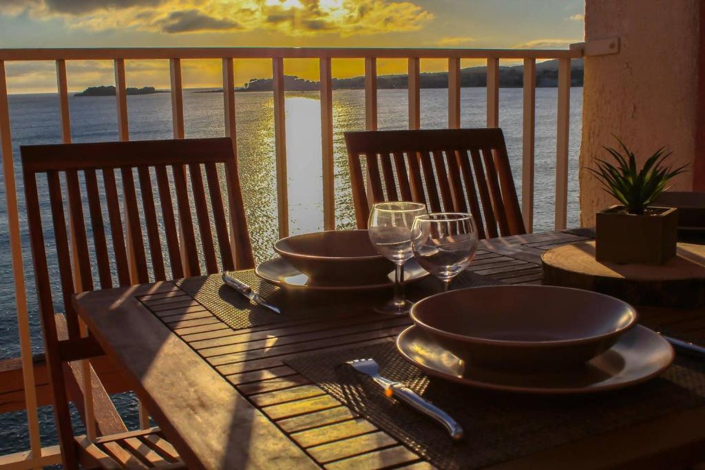 une table avec des assiettes et des verres à vin sur un balcon dans l'établissement Les pieds dans l'eau, à Sanary-sur-Mer