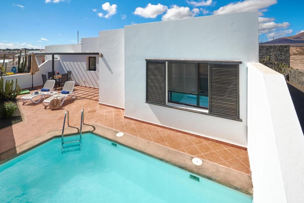 a villa with a swimming pool and a house at Bungalow María de Timanfaya - Sea and Mountains Views, Pool, WiFi, 15 minutes walk to Marina Rubicón in Playa Blanca