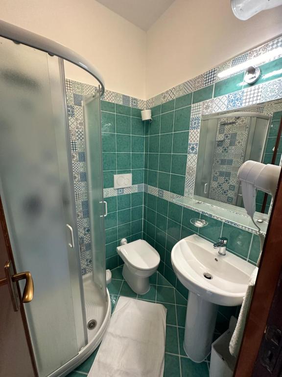 a green tiled bathroom with a toilet and a sink at Hotel Regina del Mare in Ischia