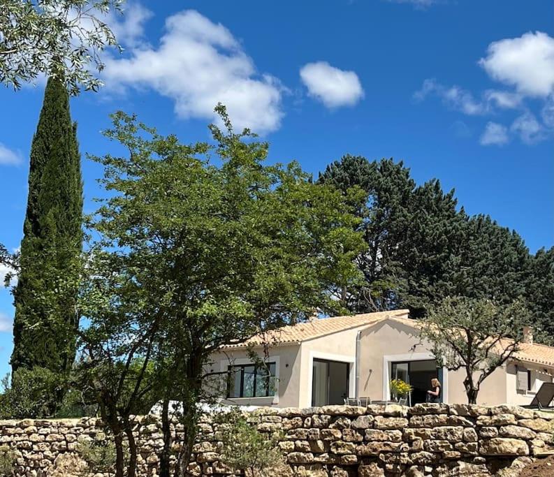 une maison blanche avec un mur en pierre et des arbres dans l'établissement Havre de paix sur Roussillon, à Roussillon