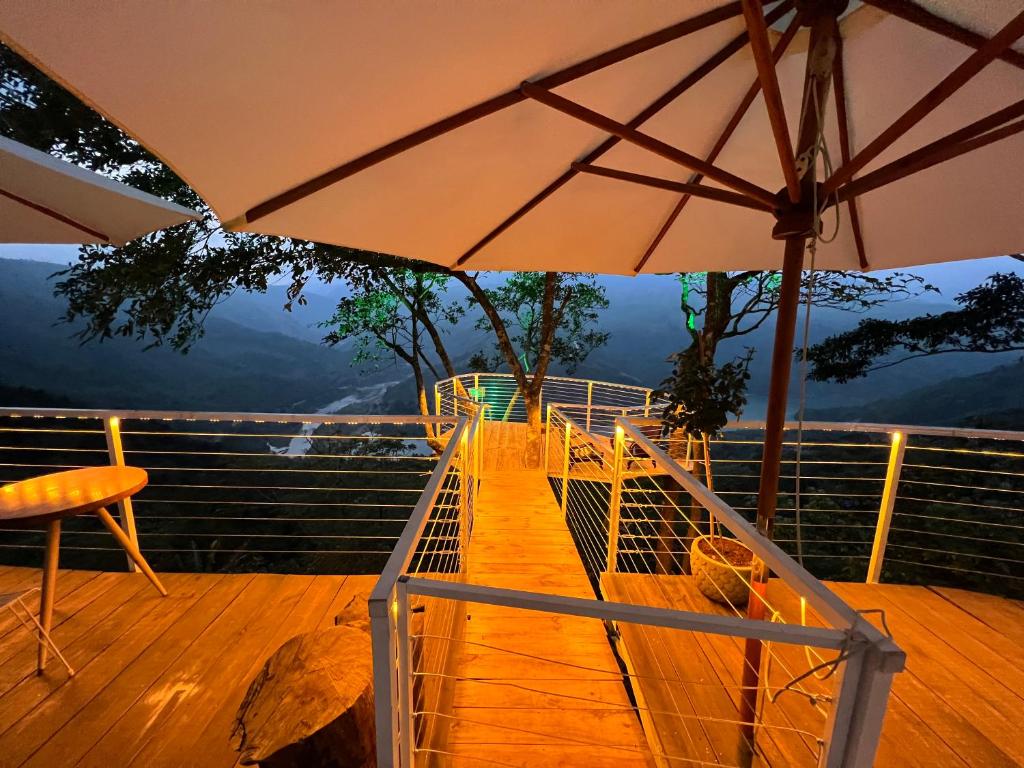 a balcony with an umbrella and a table and chairs at Retro Khe Sanh in Lao Bao