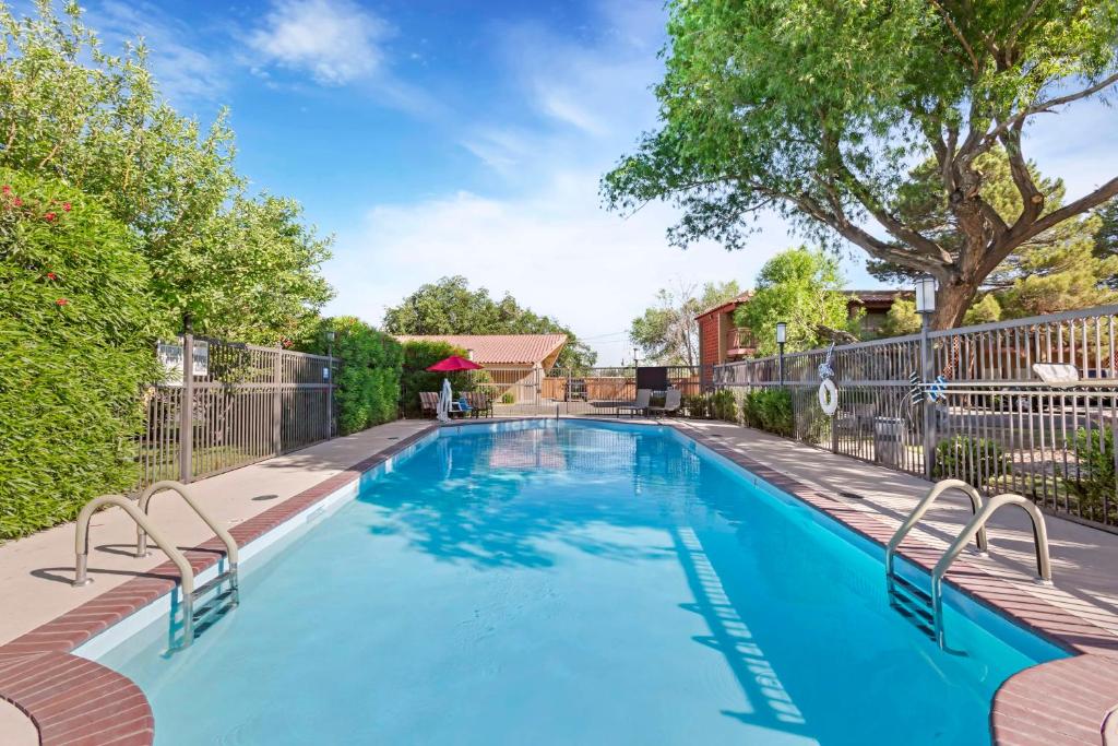 a swimming pool with chairs next to a fence at Best Western Mission Inn in Las Cruces