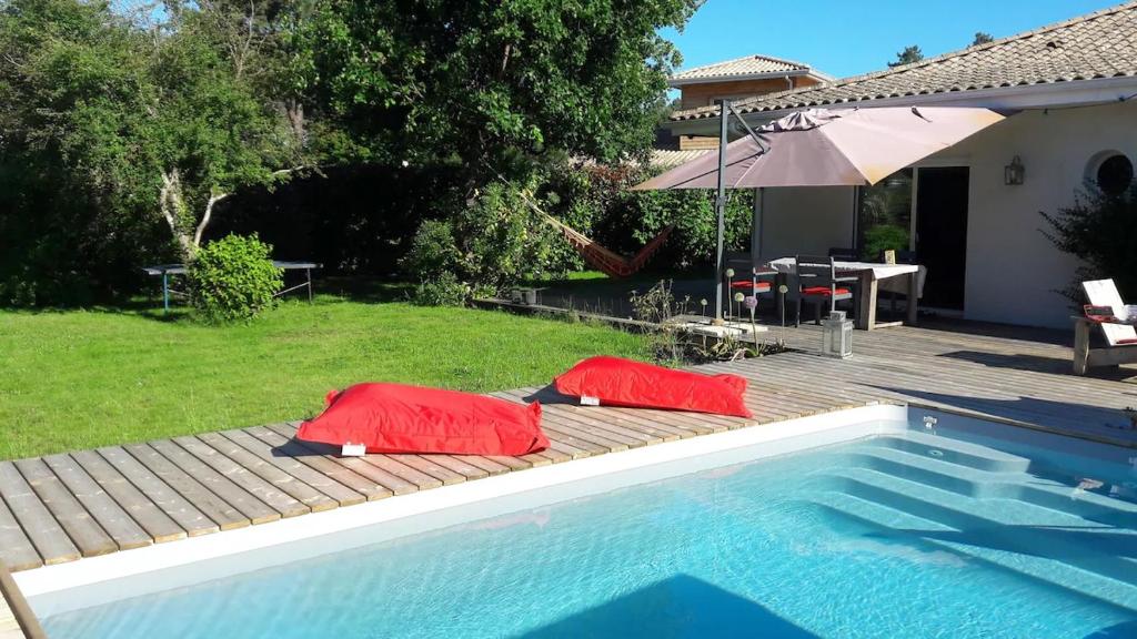 deux oreillers rouges sont assis à côté d'une piscine dans l'établissement Maison avec piscine chauffée entre océan et bassin, à Lège-Cap-Ferret
