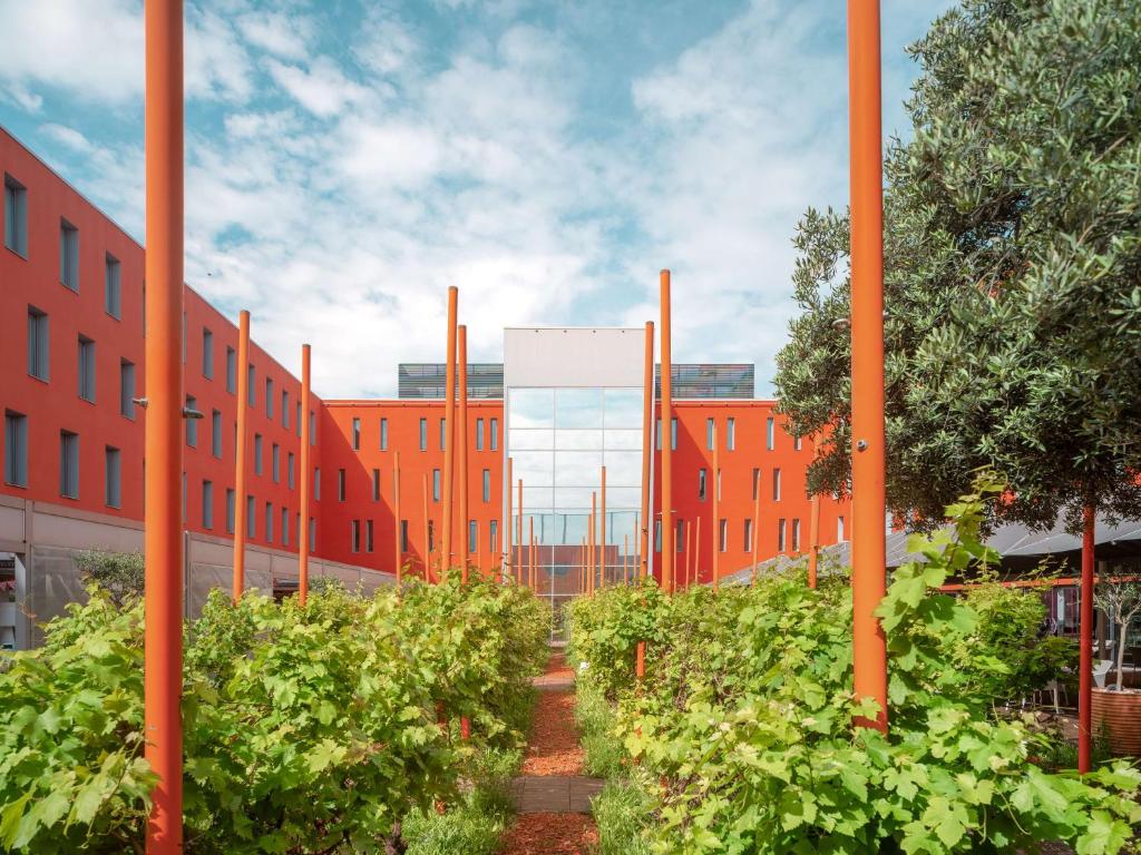 a building with orange poles and plants in front of it at Radisson Blu Hotel Toulouse Airport in Blagnac