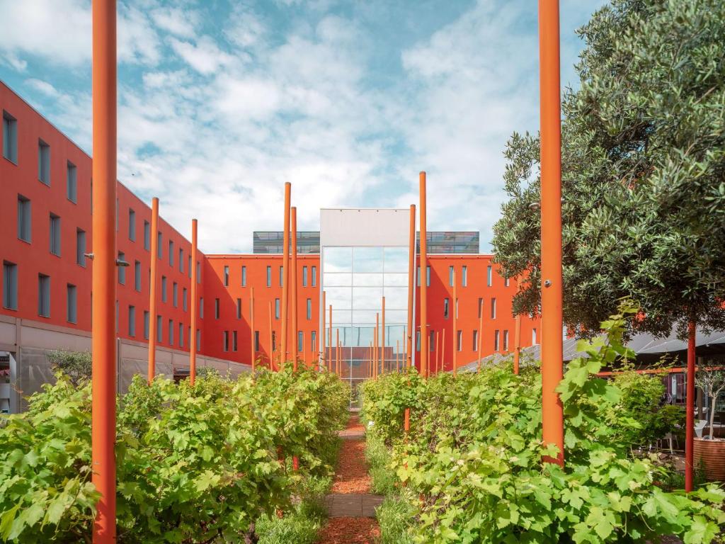 ein Gebäude mit orangefarbenen Stangen und Pflanzen davor in der Unterkunft Radisson Blu Hotel Toulouse Airport in Blagnac