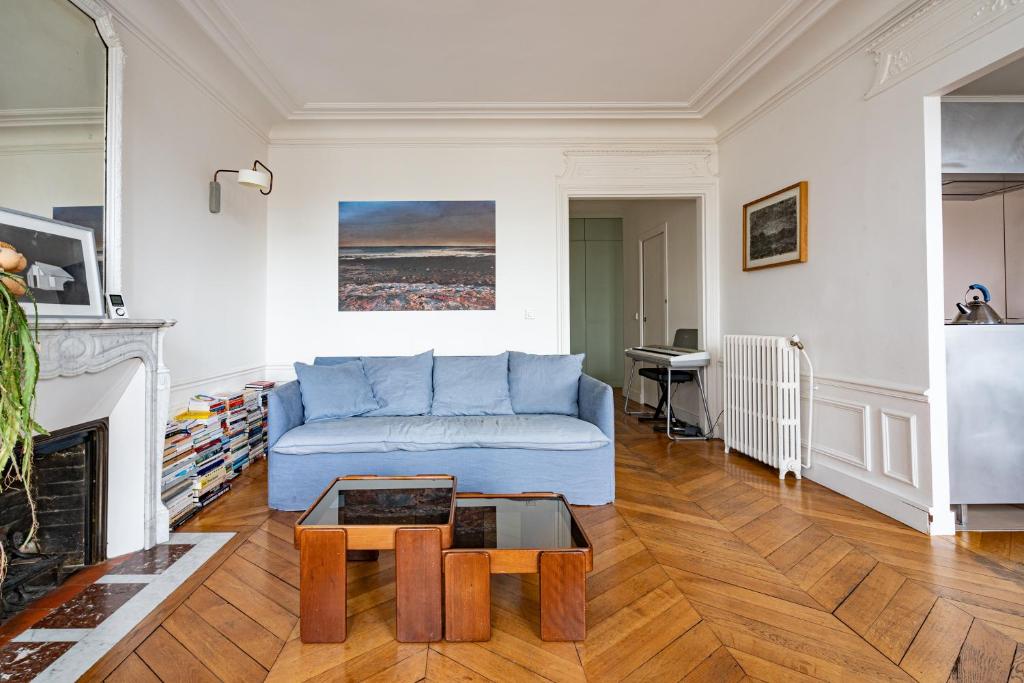 un salon avec un canapé bleu et une cheminée dans l'établissement 2 bd lovely apt facing Canal St Martin sleeps 6, à Paris