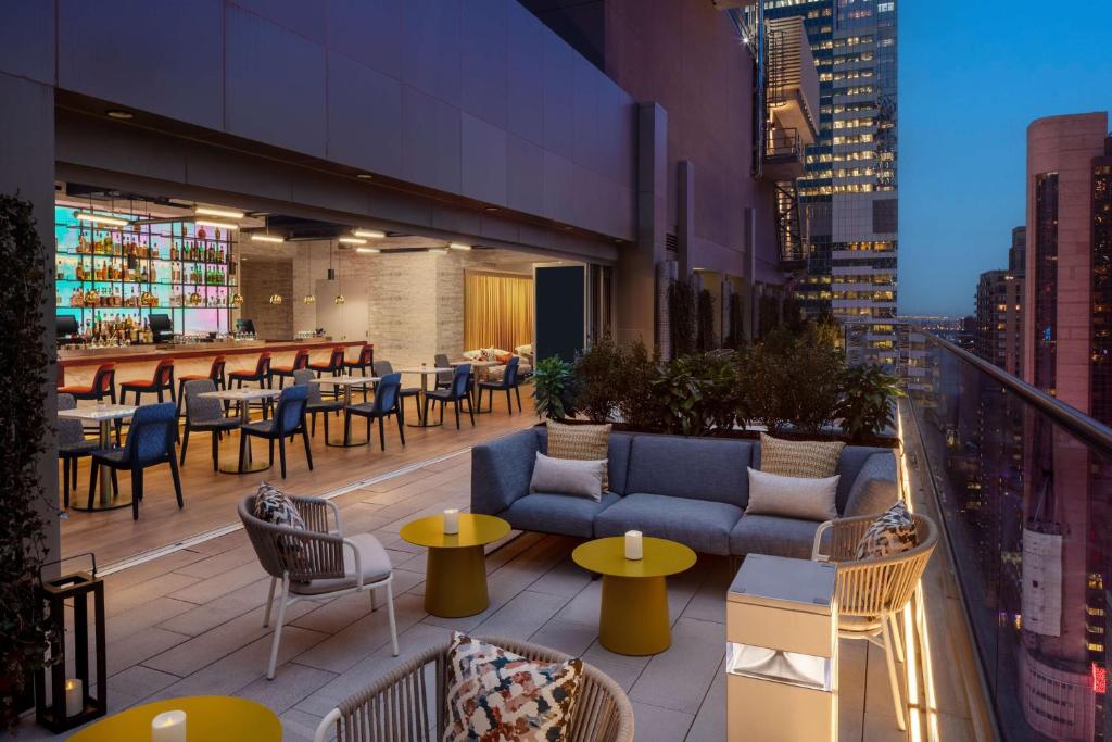 eine Dachterrasse mit Tischen und Sofas auf einem Gebäude in der Unterkunft Hampton Inn by Hilton New York Times Square in New York