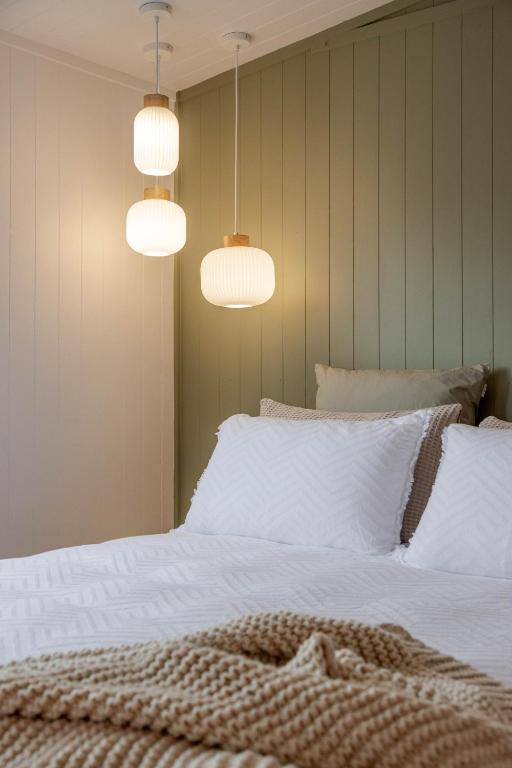 a bedroom with a bed with white sheets and two lights at The Shed in Cambridge