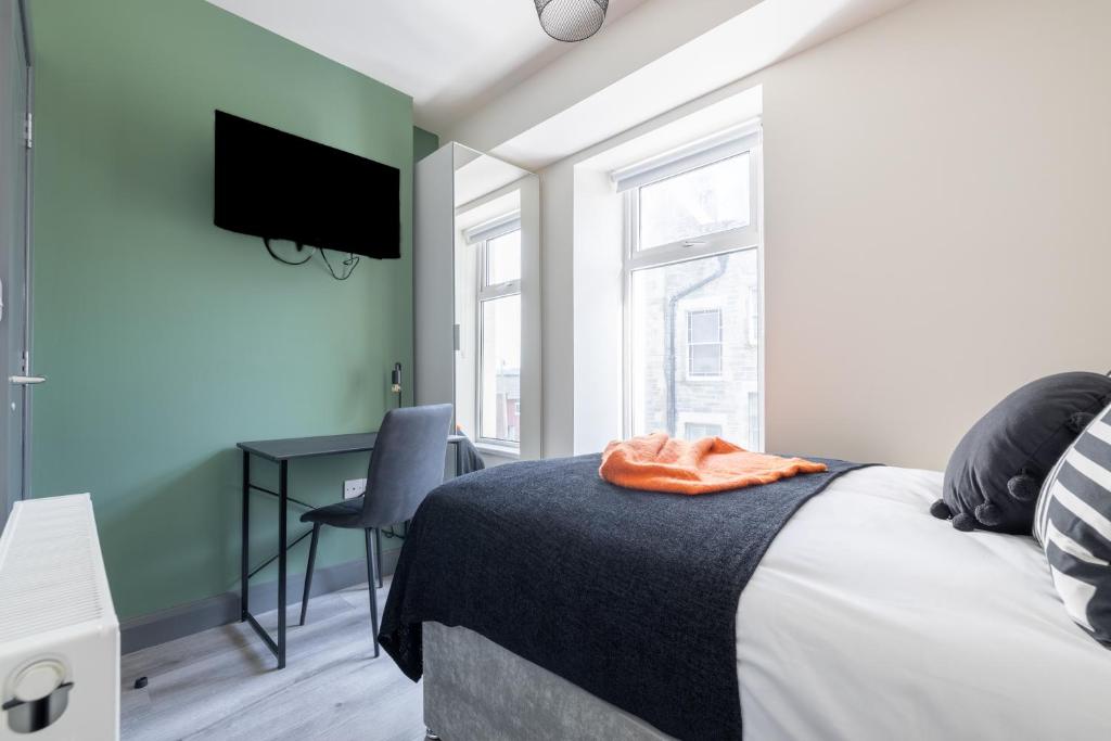 a bedroom with a bed and a desk with a television at City Rooms in Derry Londonderry