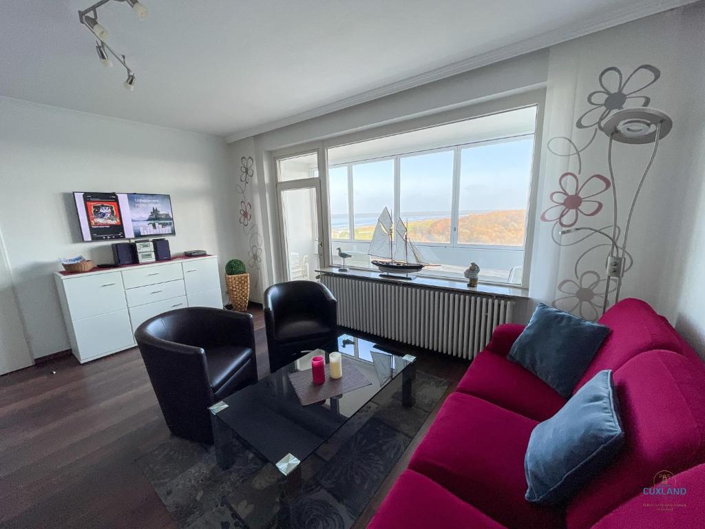 sala de estar con sofá púrpura y ventana en Haus Atlantic Döse Wohnung 708, en Cuxhaven