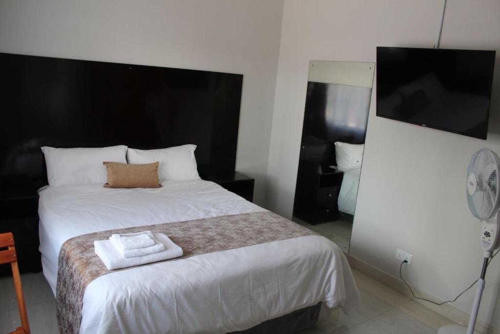 a bedroom with a bed with two towels on it at One03 Guest house in Harare