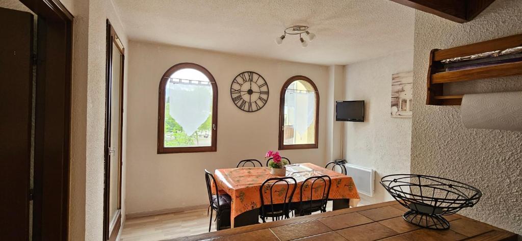 - une salle à manger avec une table, des chaises et 2 fenêtres dans l'établissement APPT T2 saisonnier en montagne, à Jausiers