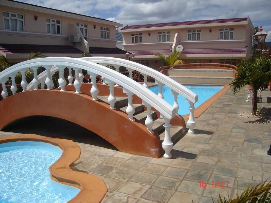 弗利康弗拉克Ideally Located, Fully Furnished, Air Cond Apartment In Flic En Flac !ONLY 5 mins walk to the beach的一座桥,在游泳池旁边