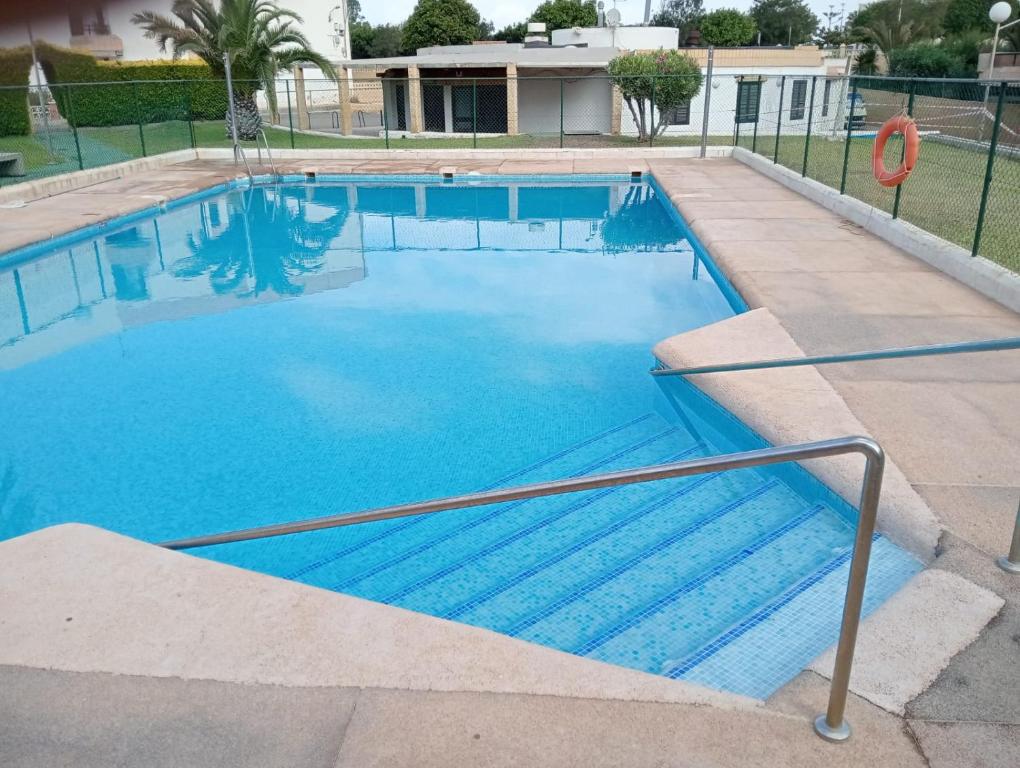 a large swimming pool with blue water and stairs at CT 288 AL - Faro's Retamar Cuddly Nest for 2 in Almería