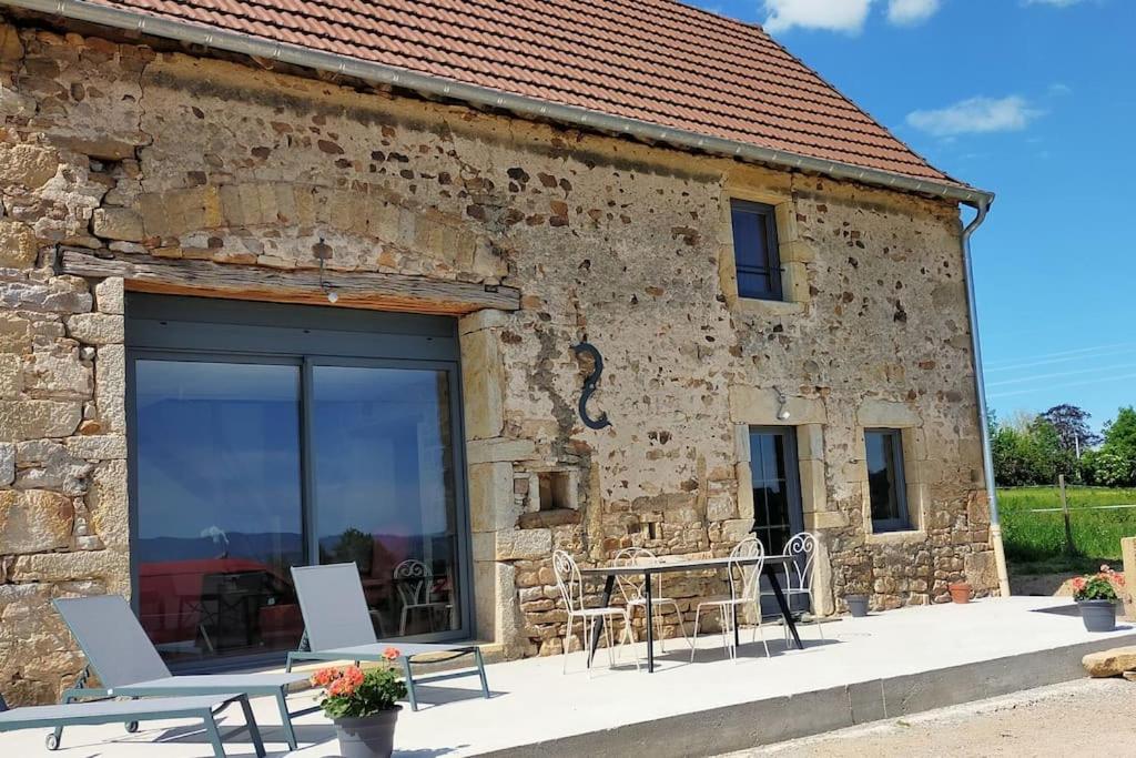 - un bâtiment en pierre avec une table et des chaises à l'extérieur dans l'établissement Fermette Brionnaise, à Saint-Laurent-en-Brionnais