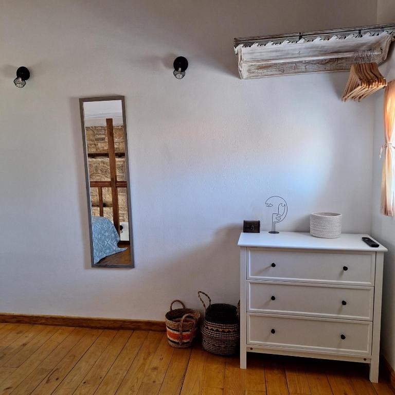 a bedroom with a white dresser and a mirror at To Pefko - Mezzanines - in Meyisti