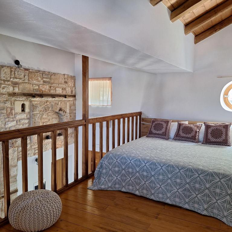 a bedroom with a bed and a stone fireplace at To Pefko - Mezzanines - in Meyisti