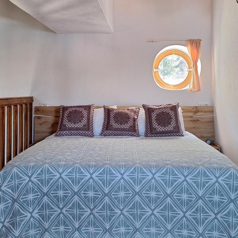 a bedroom with a blue bed with a window at To Pefko - Mezzanines - in Meyisti