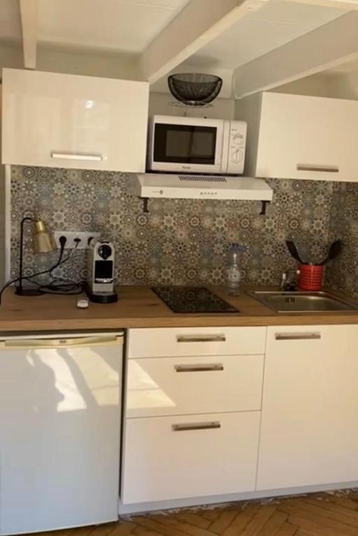 une cuisine avec des armoires blanches et un micro-ondes dans l'établissement Studio Hérold - Évasion avec Terrasse à Nice, à Nice