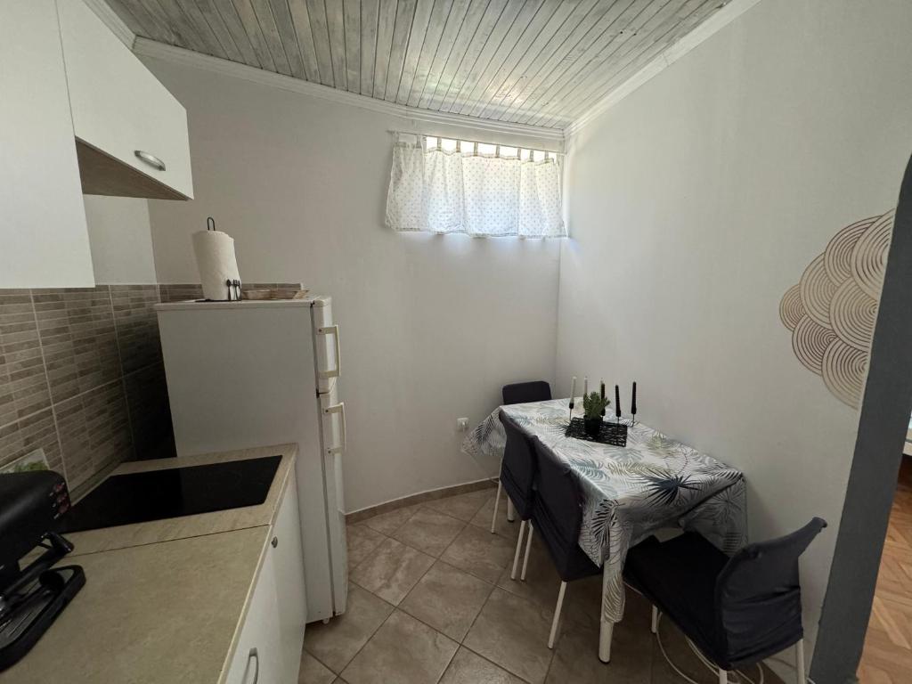 a small kitchen with a table with chairs and a window at Apartmani Luciano in Novalja