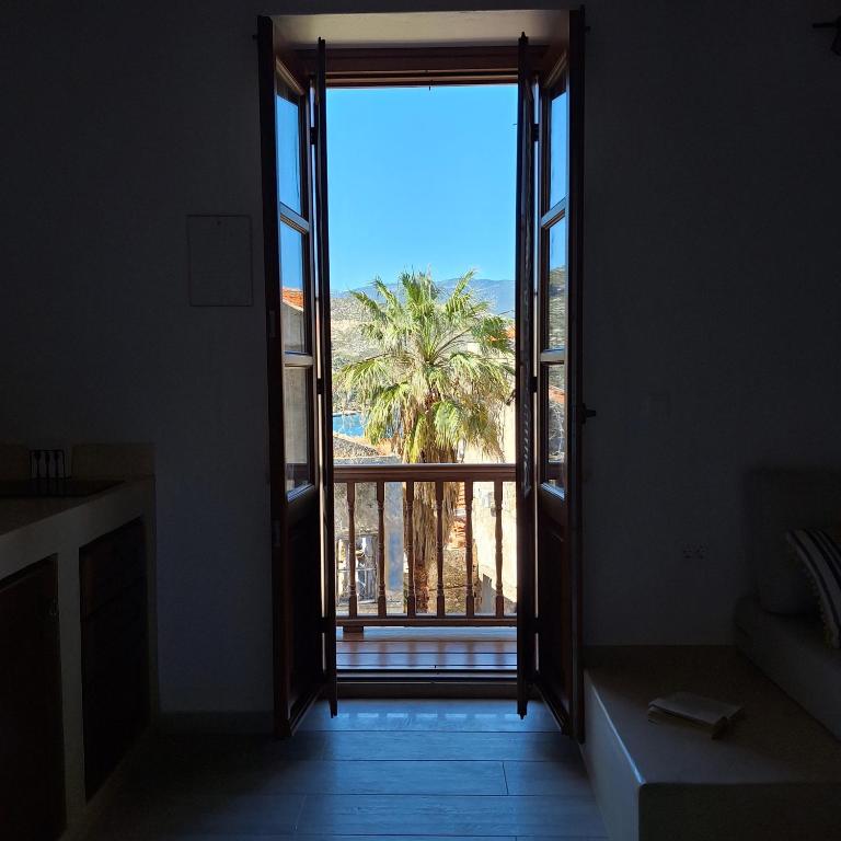 an open door with a view of a palm tree at To Pefko - Mezzanines - in Meyisti