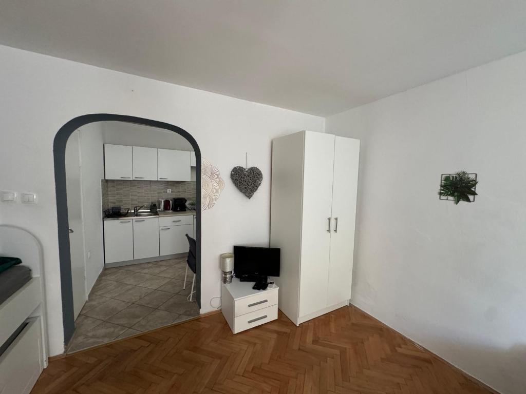 a white living room with a mirror and a television at Apartmani Luciano in Novalja