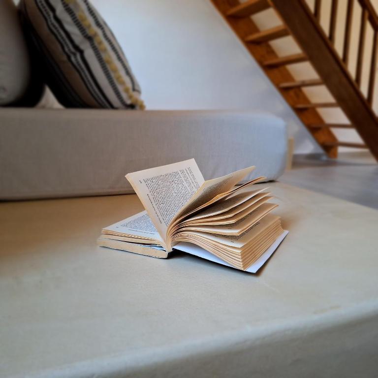 an open book sitting on a table with a laptop at To Pefko - Mezzanines - in Meyisti