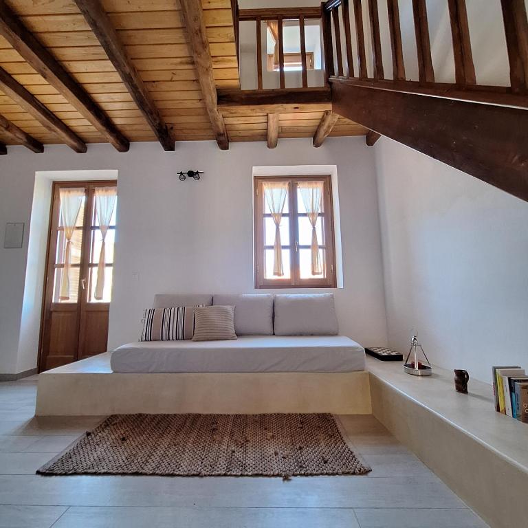 a bedroom with a bed in a room with windows at To Pefko - Mezzanines - in Meyisti