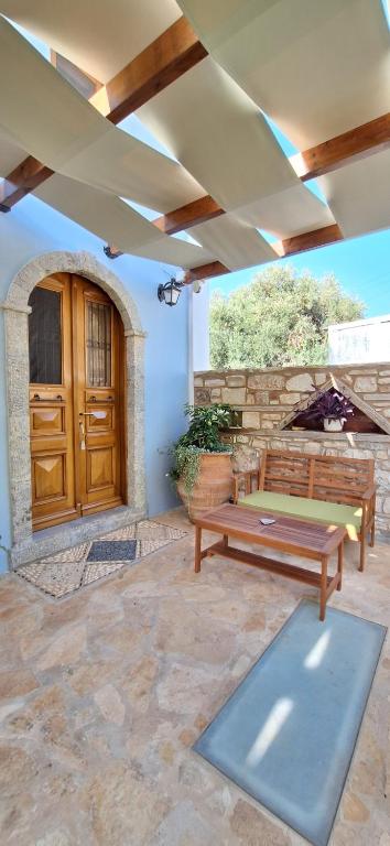 a patio with a bench and a wooden door at To Pefko - Mezzanines - in Meyisti
