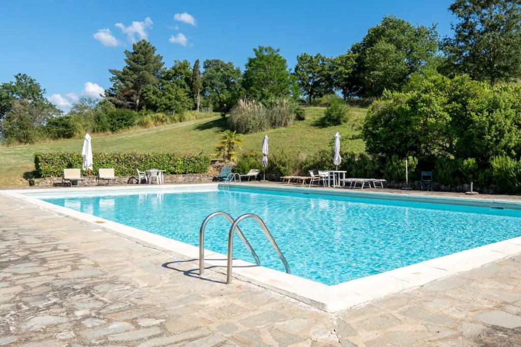 una piscina con mesas y sombrillas junto a ella en Villa Badia a Ruoti, en Badia a Ruoti