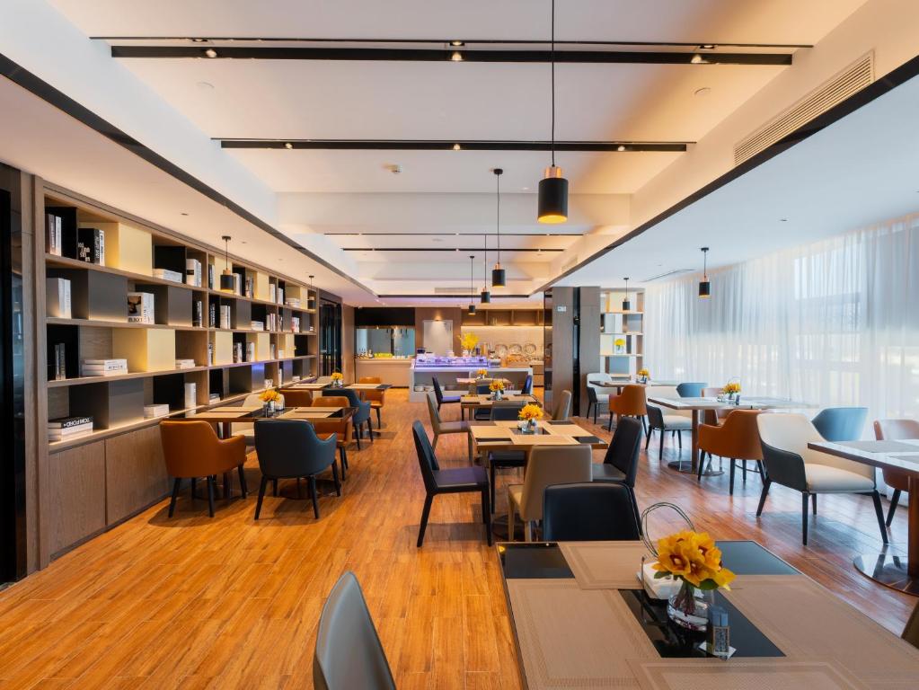 武汉宜尚酒店(武汉经开永旺体育中心店)的一间带桌椅的餐厅和一间图书馆