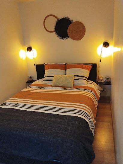 - une chambre avec un lit et deux lumières sur le mur dans l'établissement Maison de village appartement RDC avec terrasse, à Gy