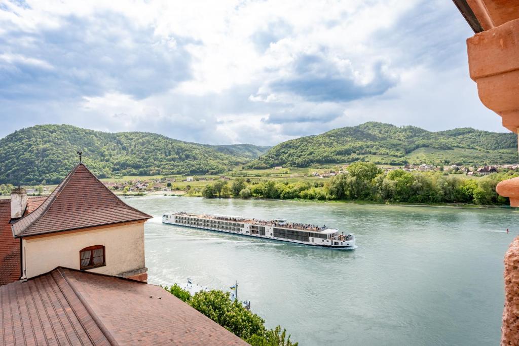 a boat on a river with mountains in the background at Hotel Schloss Dürnstein in Dürnstein