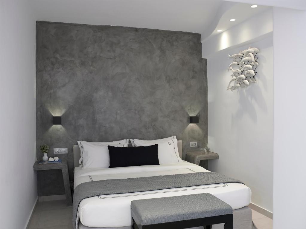 um quarto com uma cama grande e uma parede cinzenta em Kalisti Hotel & Suites em Fira