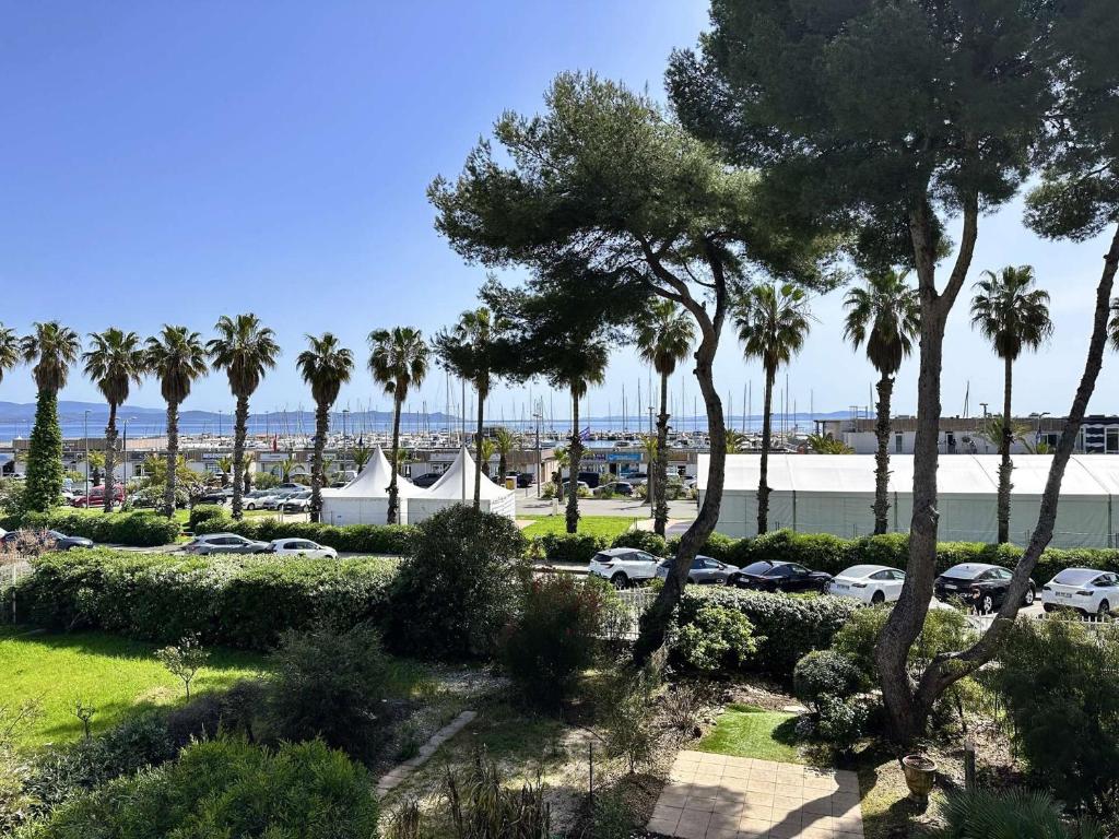 une vue d'un parc avec des palmiers et une tente dans l'établissement Le Palm, appartement climatisé pour 4 personnes avec vue mer et piscine sur le Port d'Hyères, à Hyères
