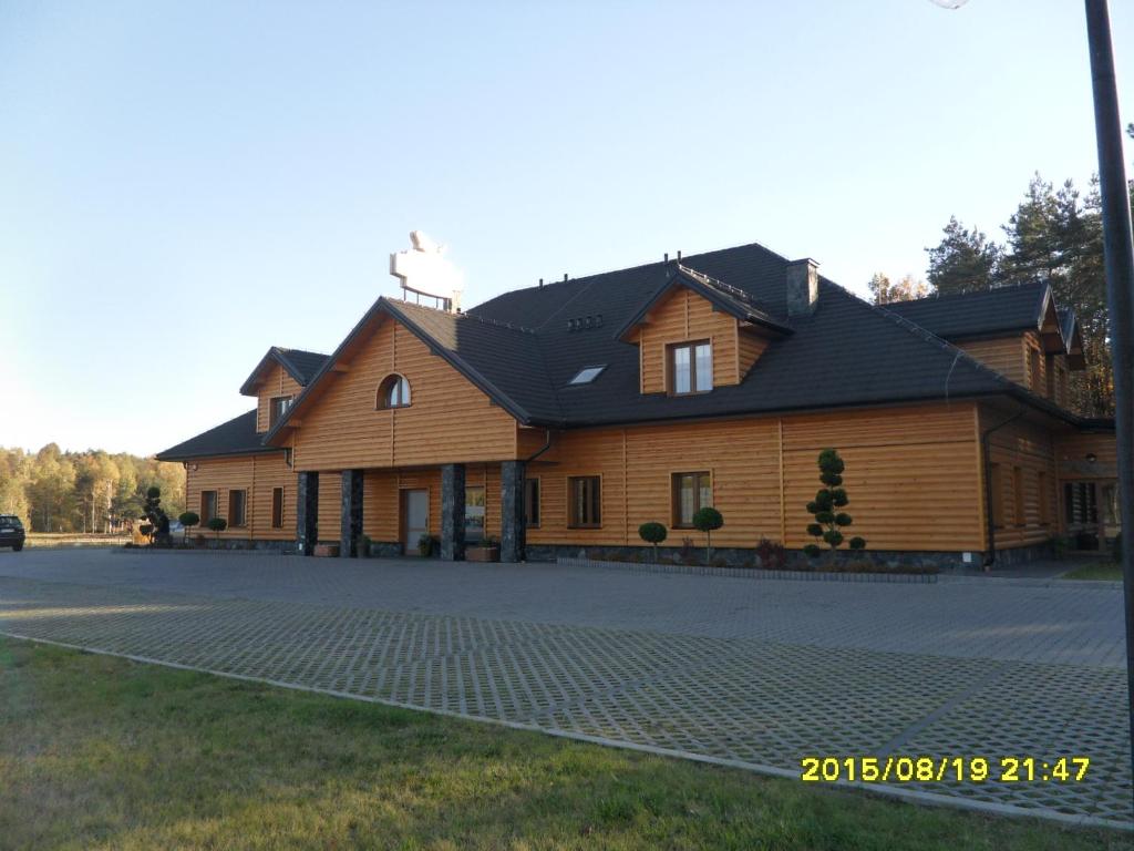 a large wooden house with a black roof at Karczma Dolina Pstrąga in Machowa