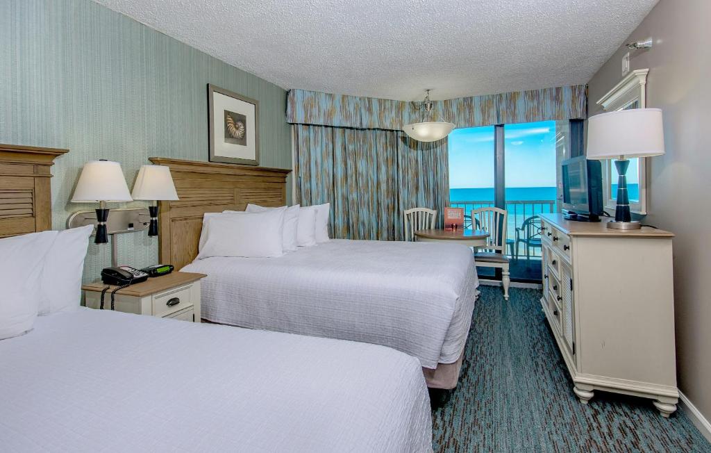 a hotel room with two beds and a view of the ocean at The Strand - A Boutique Resort in Myrtle Beach