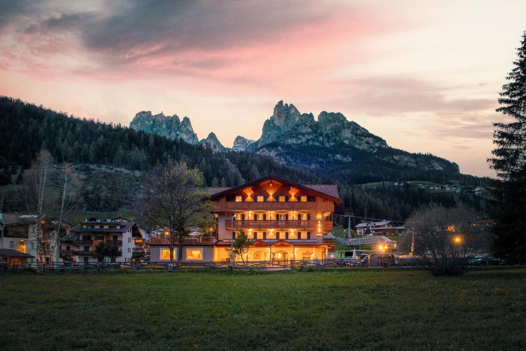 un edificio en un campo con montañas en el fondo en X Alp Hotel en Pozza di Fassa