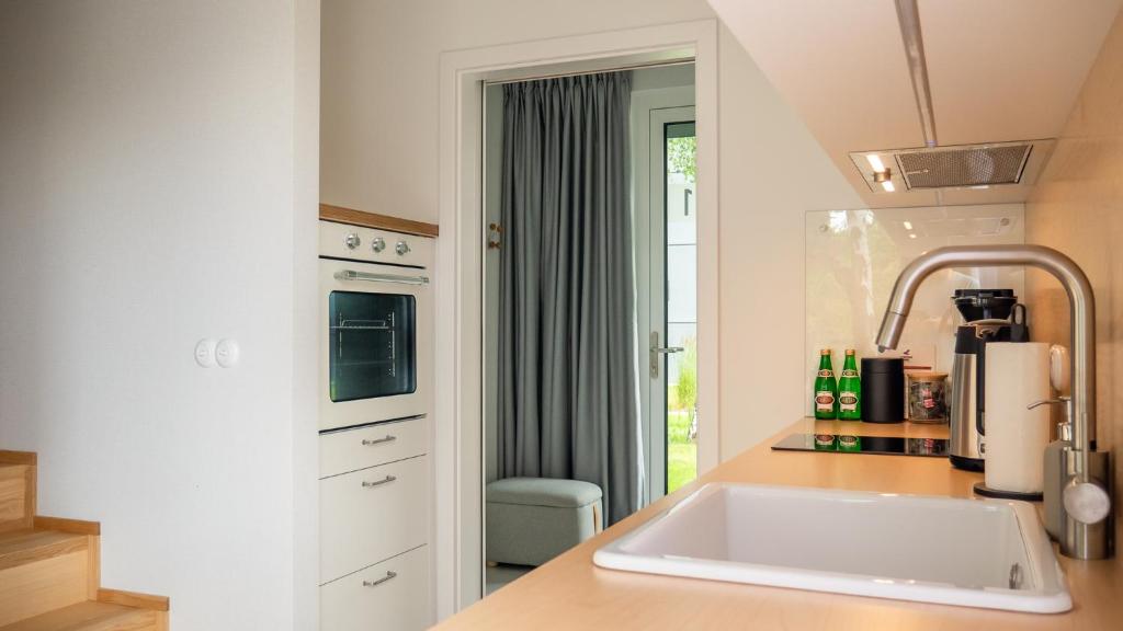 a white kitchen with a sink and a window at Apartament w willi z ogrodem SurfingBird Dźwirzyno in Dźwirzyno