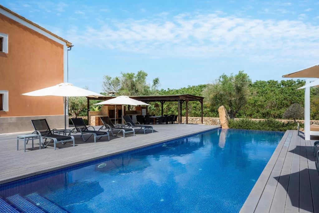 a swimming pool with chairs and umbrellas on a deck at Finca Conies Romaní in Manacor