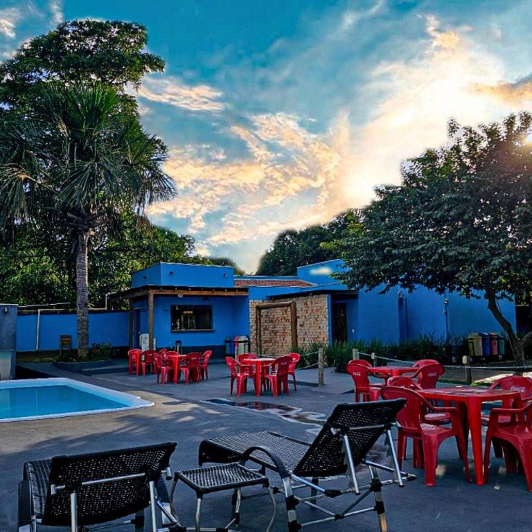 a group of red tables and chairs next to a building at Pousada Bom Jardim in Estivado