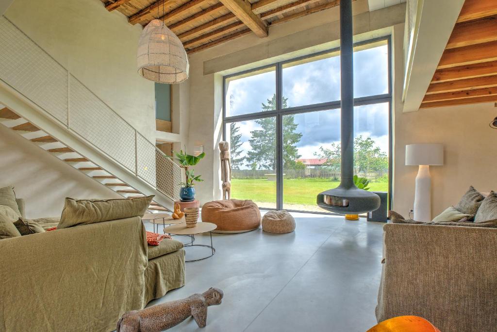 un salon avec un canapé et une grande fenêtre dans l'établissement Le Domaine de la Férédie, à Vieux-Mareuil