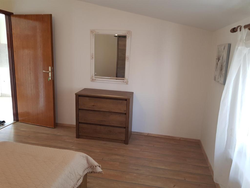 ein Schlafzimmer mit einem Bett, einer Kommode und einem Spiegel in der Unterkunft Apartmani Kornatska in Tribunj