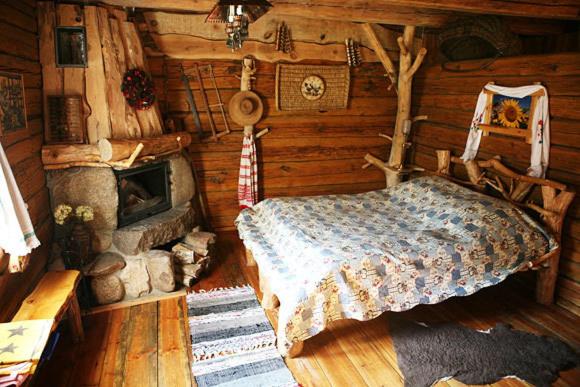 a bedroom in a log cabin with a bed and a fireplace at Agrousadba Nad Nemanom in Byarozawka