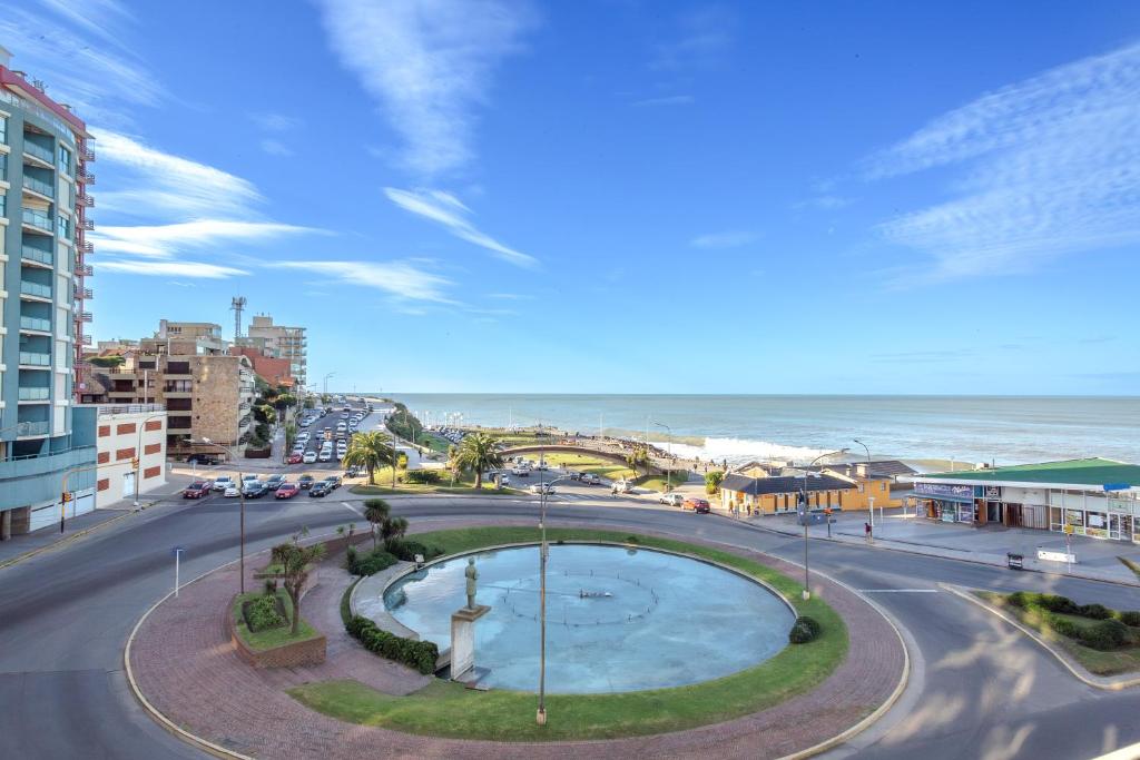 a view of a street with a fountain and the ocean at Hotel Iruña in Mar del Plata