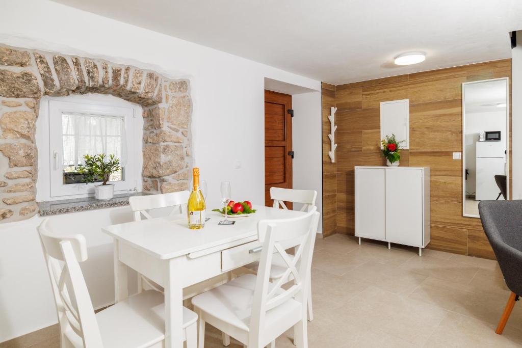 a kitchen and dining room with a white table and chairs at Holliday house Smokvica in Jadranovo