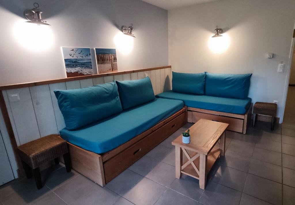 une salle d'attente avec des coussins bleus et une table dans l'établissement Argousiers 11, à Fort-Mahon-Plage
