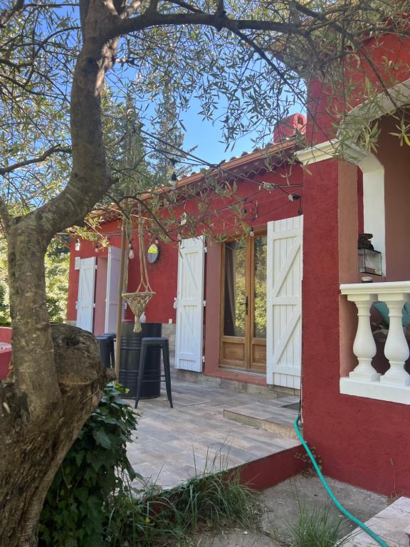 une maison rouge avec un arbre devant elle dans l'établissement Villa au cœur de la Provence, à Évenos