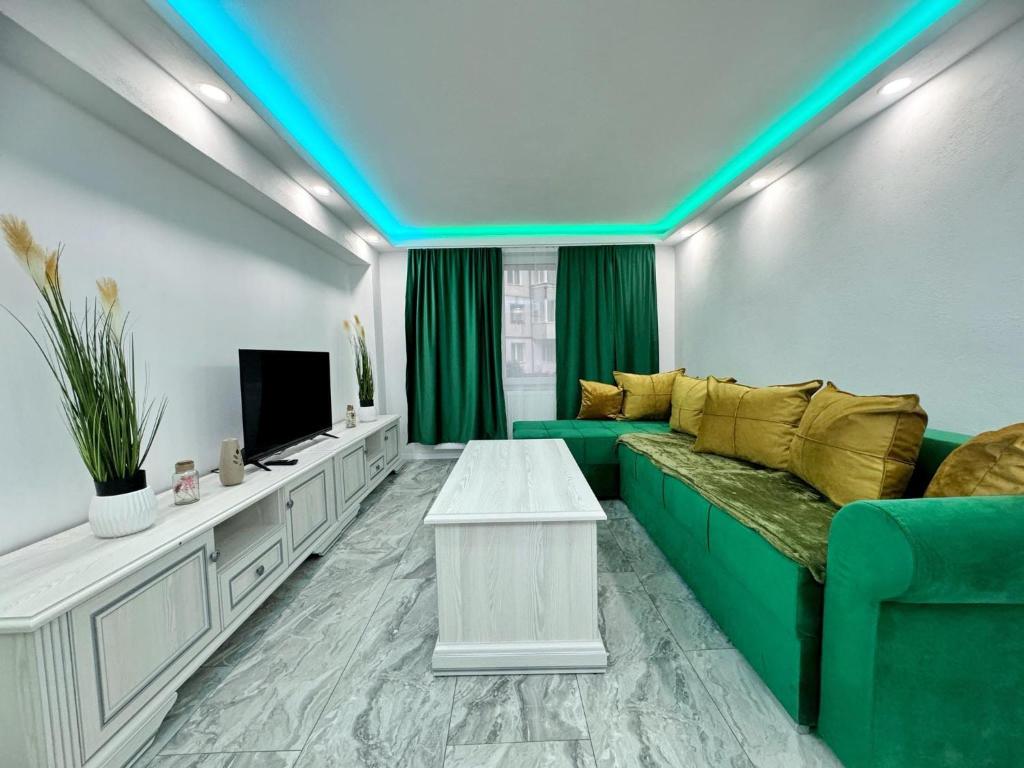 ein Wohnzimmer mit einem grünen Sofa und einem Fernseher in der Unterkunft Citadel Majestic Apartament in Sighişoara