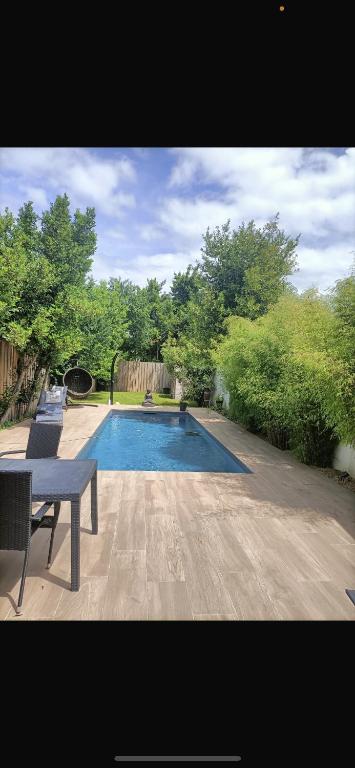 - une piscine avec une table et des chaises dans la cour dans l'établissement Villa du Bouscat, à Le Bouscat